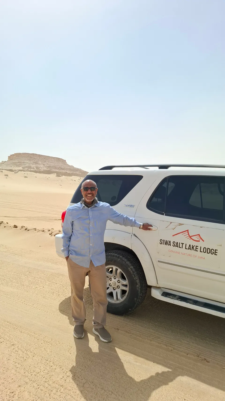 The lodge owner beside the lodge vehicle in the desert